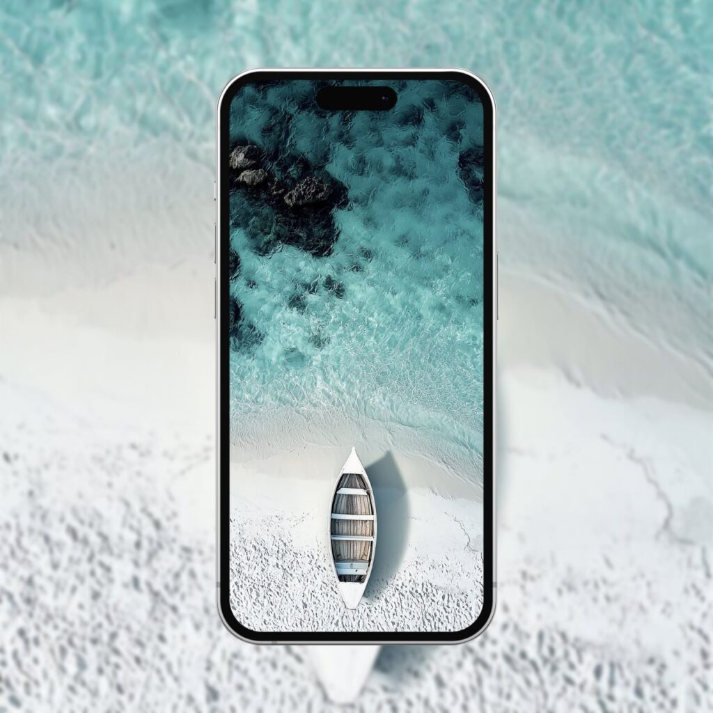 4K Tropical Beach Boat Wallpaper Mockup: An iPhone showcasing the serene aerial view of a wooden boat on a white sand beach, with the turquoise water gently lapping the shore.